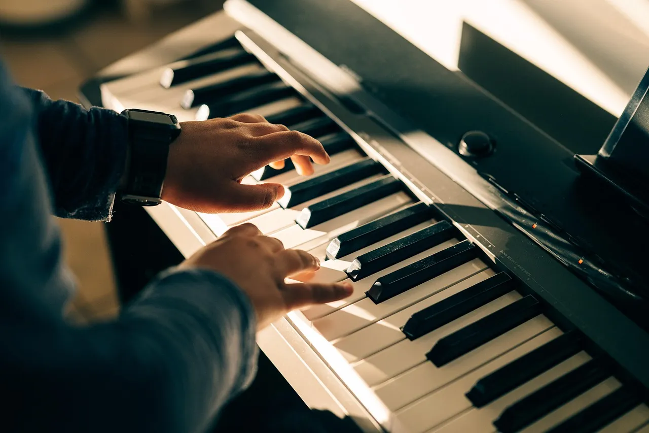 Des mains posées sur le clavier d'un piano dans une lumière de clair-obscur