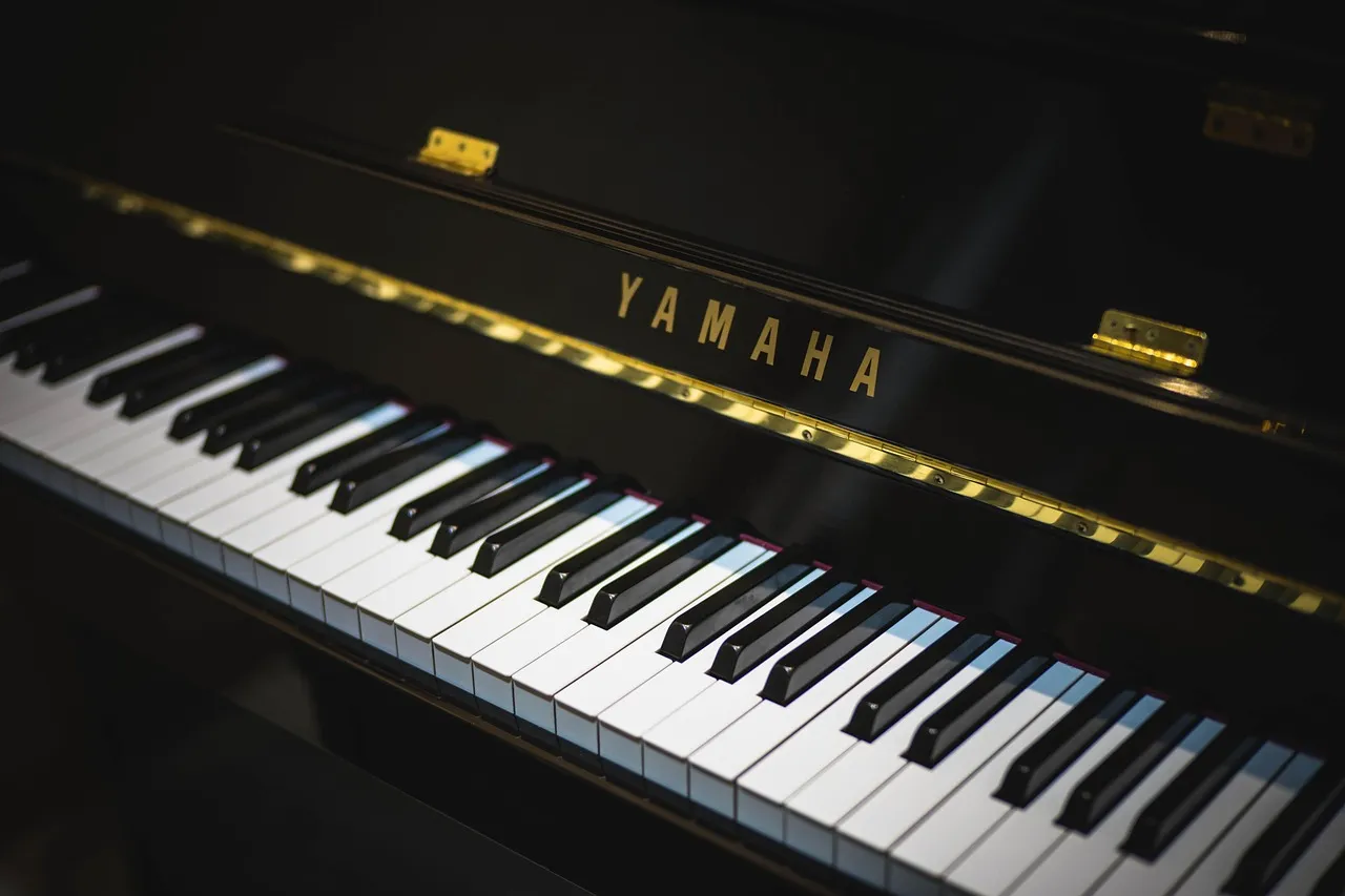 Un piano à queue vide dans l'obscurité, éclairé par une lumière chaude